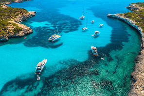 Aerial view of boats and luxury yachts in transparent sea at sunny day in Mallorca, Spain in summer. Sea coast. Colorful seascape with marina bay, azure water. Top view from drone of shore. Travel