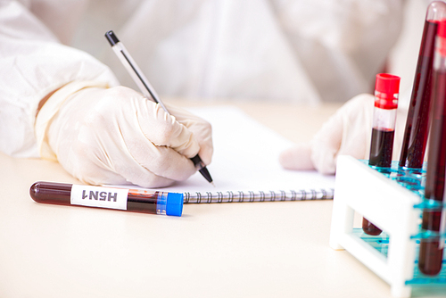 Young handsome lab assistant testing blood samples in hospital