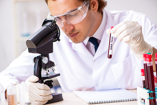 Young handsome lab assistant testing blood samples in hospital