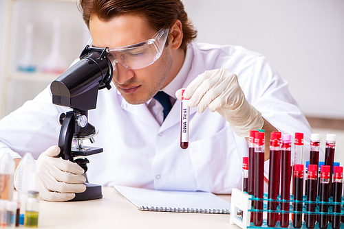 Young handsome lab assistant testing blood samples in hospital