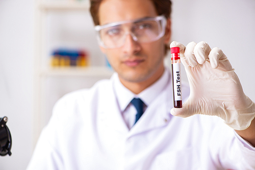 Young handsome lab assistant testing blood samples in hospital