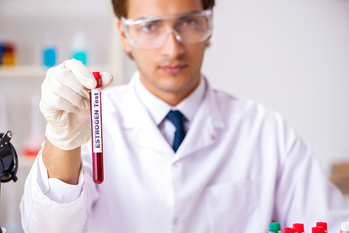 Young handsome lab assistant testing blood samples in hospital