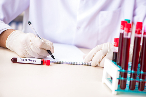 Young handsome lab assistant testing blood samples in hospital