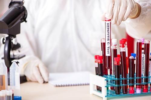 Young handsome lab assistant testing blood samples in hospital