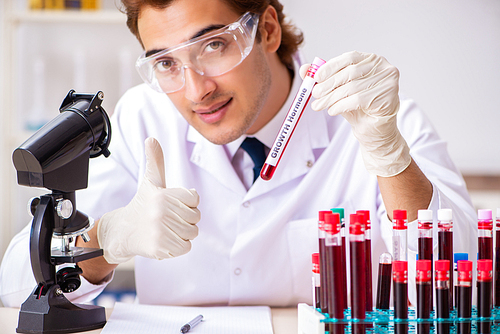 Young handsome lab assistant testing blood samples in hospital