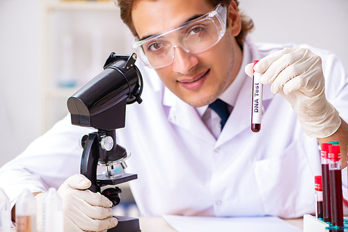 Young handsome lab assistant testing blood samples in hospital