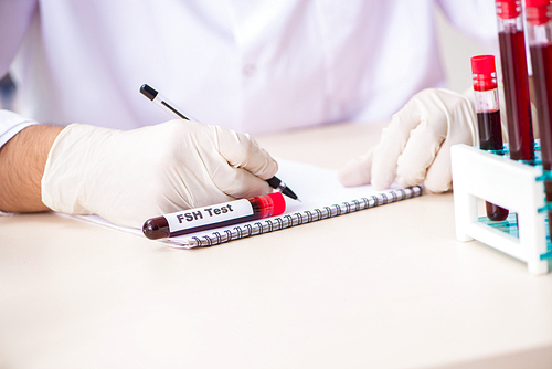 Young handsome lab assistant testing blood samples in hospital