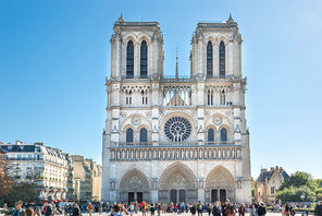 Notre Dame de Paris - people at famous cathedral with sun and blue sky