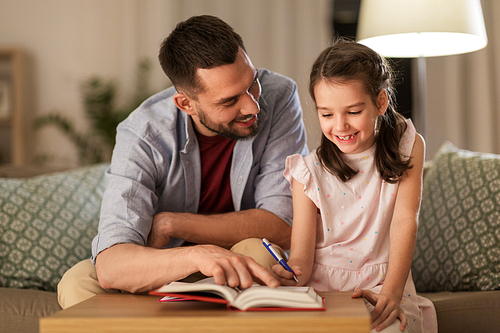 education, family and homework concept - happy father and daughter with book doing homework at home