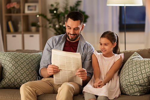 family, leisure and people concept - happy father and daughter reading newspaper at home