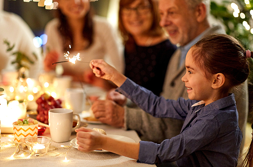 celebration, holidays and people concept - happy girl with sparkler at family tea party