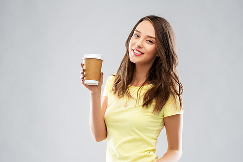 takeaway and people concept - smiling young woman or teenage girl in yellow t-shirt with coffee cup over grey background