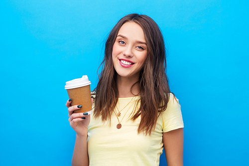 takeaway and people concept - smiling young woman or teenage girl in yellow t-shirt with coffee cup over bright blue background