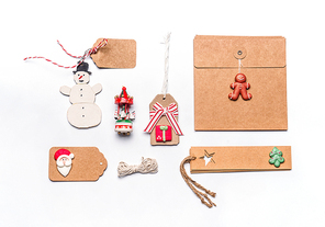 Christmas gift wrapping concept. Flat lay of various craft eco paper cardboard package and tags with vintage snowman and decoration on white desktop background, top view.