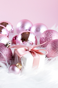 Pink Christmas decorations with gift box on white fur background