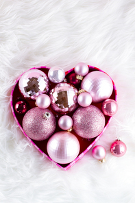Pink Christmas decorations in box on white fur background
