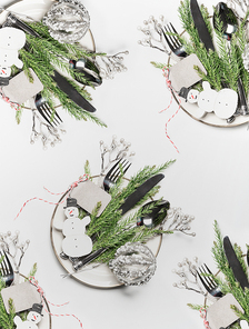 Christmas table setting with plates, cutlery , fir branches on white background, top view, flat lay. Holiday concept
