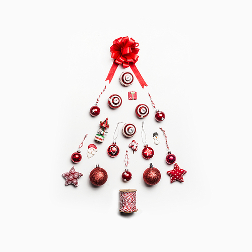 Christmas tree made with various festive holiday objects: balls, gift, ribbons,Santa, decorations, star, snowman on white background. Flat lay, top view