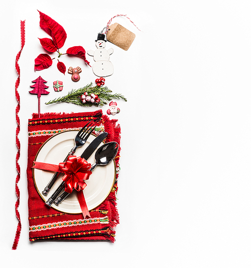 Christmas concept. Various holiday objects: table place setting with cutlery and decorations, fir branches, snowman, cones, tags, ribbon and poinsettia on white background. Flat lay, top view