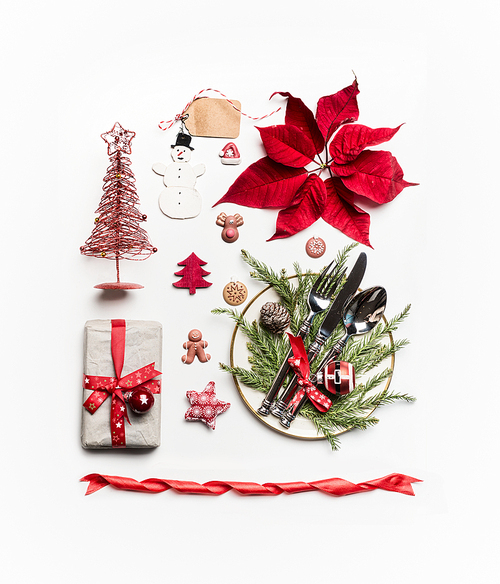 Christmas concept. Various holiday objects: gift, Christmas tree, table place setting with cutlery and decorations, fir  branches, pine cones and poinsettia on white background. Flat lay, top view