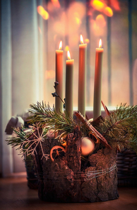 Cozy Christmas time at home.  Advent wreath with four burning candles. Winter decor interior with warm bokeh lighting. Christmas eve