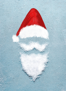 Santa Claus portrait symbol with painted Santa hat and beard with mustache made with snow on blue background with copy space for your design. Creative Christmas minimal holiday concept