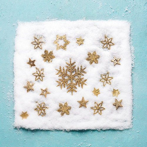 Christmas golden snowflakes pattern in snow on light blue background, top view. Flat lay. Winter composition and holiday concept