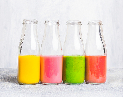 colorful smoothies assortment  in glass bottles on light table, side view. superfoods and health or detox   food concept.