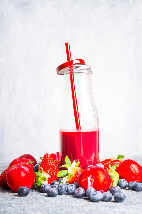 red smoothie bottle with straw and ingredients on light wooden background, side view. healthy lifestyle and detox or   food concept
