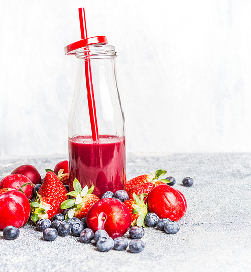 red fruits smoothie in bottle with  straw and fresh berries ingredients, front view, copy space