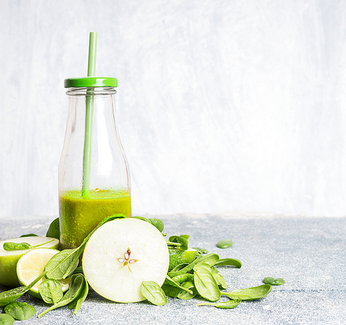 Fresh green smoothie in bottle  with apple and spinach on light background, front view.  Healthy, diet or detox beverage concept