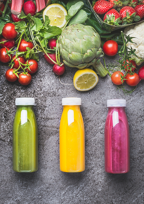 Variety of colorful Smoothies or juices beverages drinks in bottles with fresh ingredients: fruits ,berries  and vegetables on gray concrete background , top view.  Healthy Food concept