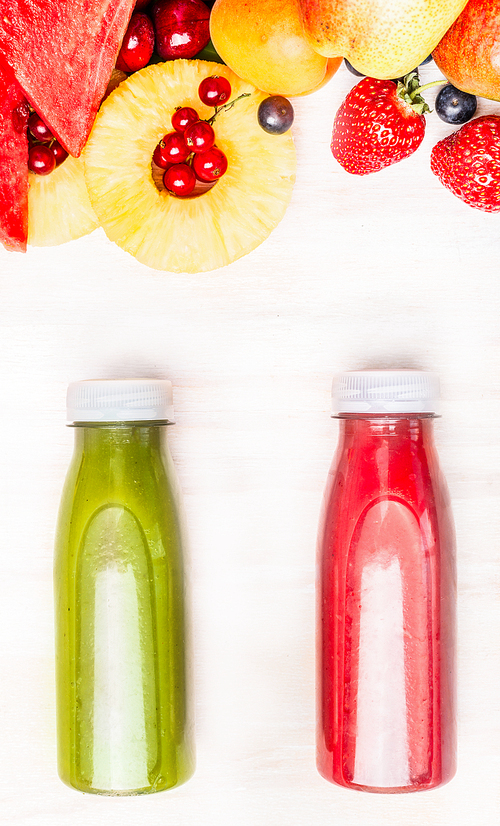 Tasty and healthy summer beverages in bottles with fruits and berries ingredient. Red and green smoothie or juice on white wooden background, top view