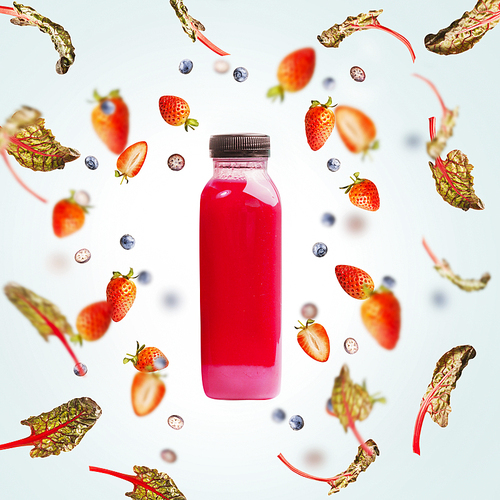 Pink smoothie bottle with flying berries and chard leaves on light blue background. Healthy detox beverages,  dieting, clean eating, vegetarian, vegan, fitness or healthy lifestyle concept