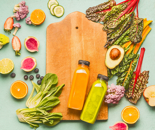 Smoothie making concept. Various healthy fresh fruits and vegetables with bottles on light mint table background with cutting board, top view , frame. Detox, dieting and clean eating