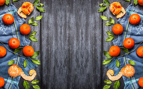 Fresh tangerines with leaves on blue rustic wooden background, top view, place for text.