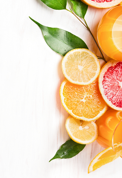 Citrus  juice and sliced  fruits: orange, lemon and grapefruit on white wooden background
