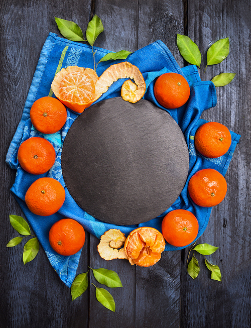 tangerine wreath whit green leaves on dark wooden with slate and blue towel, food background, top view