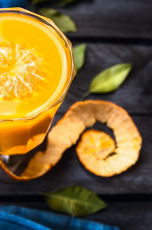 tangerine juice in glass on dark blue wooden background