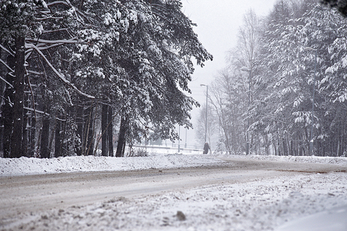 Snowfall and sleet on winter road. Ice snowy road. Winter snowstorm. Black ice and blizzard.