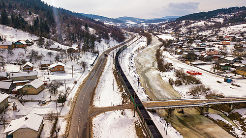Winter travel. Train and bus moving in winter valley. Aerial view of river Dniester in Carpathian mountains.