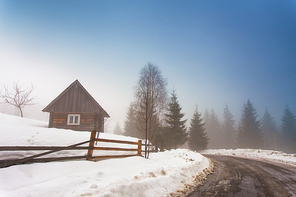 Lone house in mountain village. Foggy weather and melting snow on mountain country road in Carpathians. Weather forecast for early spring. Spring coming