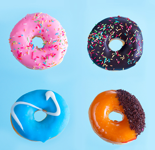 Four sweet doughnuts with sprincles on blue