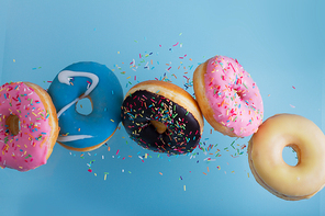 flying doughnuts - mix of multicolored sweet donuts with sprinkel on blue background