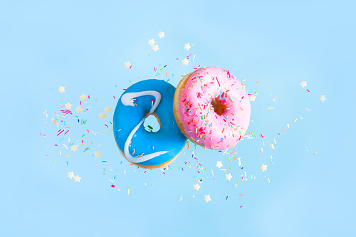 two flying sweet doughnuts - pink and blue, with sprinkles on blue