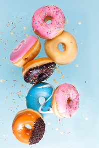 flying doughnuts scene - mix of multicolored sweet donuts with sprinkel on blue background