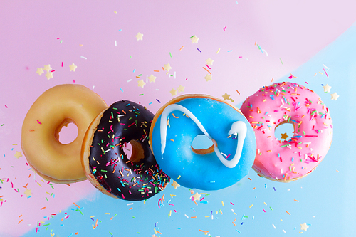 falling doughnuts border - mix of multicolored sweet donuts with sprinkles on blue and pink background