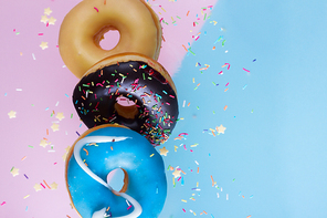 flying doughnuts border - mix of multicolored sweet donuts with sprinkles on blue and pink background