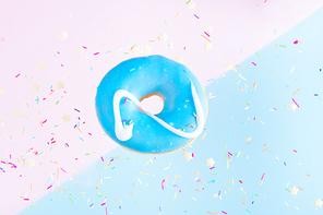 one sweet doughnut with sprinkles on blue and pink abstract background with copy space