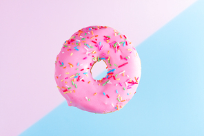 one falling sweet doughnut on blue and pink abstract background with copy space